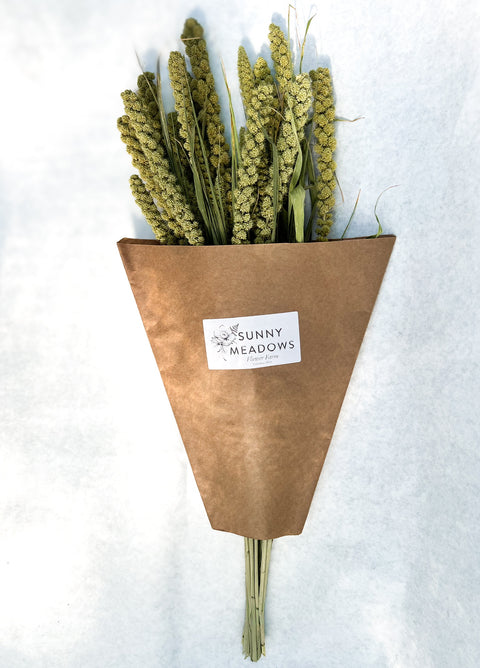 Bouquet of dried plants in a brown paper cone with 'Sunny Meadows' label on a white background